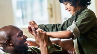 A military veteran playing with his daughter on the couch
