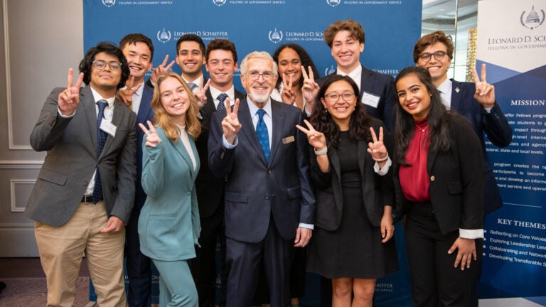 A group of Leonard D. Schaeffer Fellows in Government Service pose for a photo holding the USC