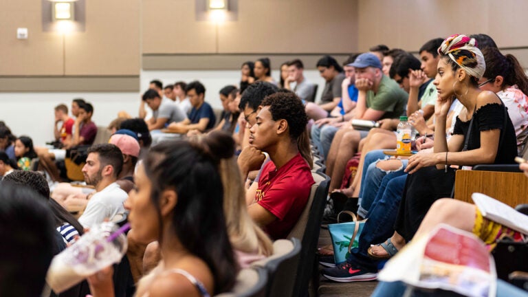 Students sit and listen in a lecture hall at USC.