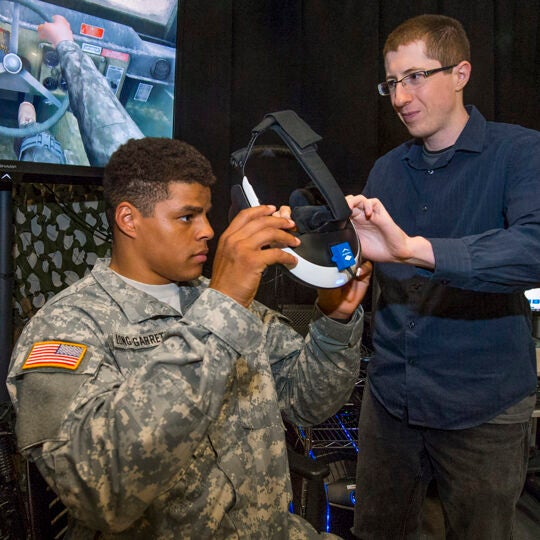 United States Military Academy West Point cadet, Jareth Long-Garrett is helped into a virtual reality headset by ICT technical project specialist Andrew Leeds. As he tries the post-traumatic stress therapy program Bravemind, Wednesday, July 20, 2016. (USC Photo/Gus Ruelas)