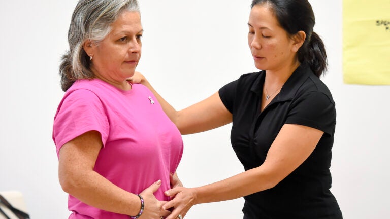 Instructor working with class attendee during free exercise class for cancer survivors