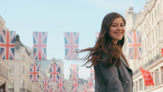 A USC student smiles and poses in front of several flying UK flags.