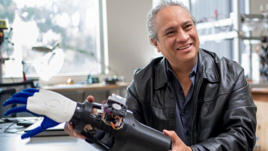 Francisco Valero-Cuevas holding a robotic hand.