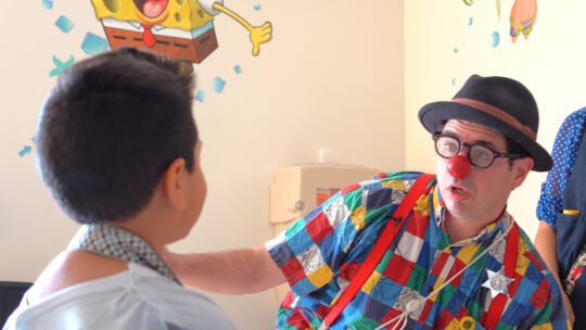 A medical clown entertains a child patient