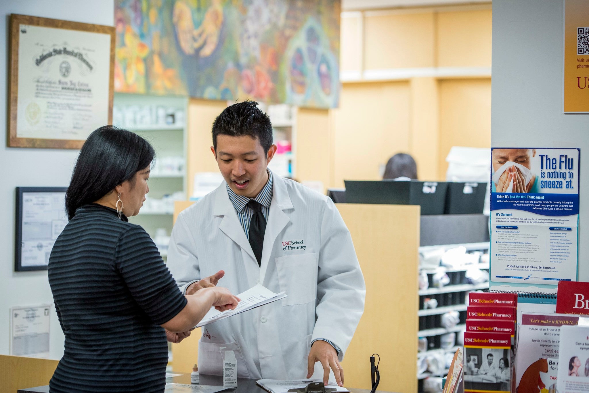 USC School of Pharmacy pharmacist helping a patient with paperwork