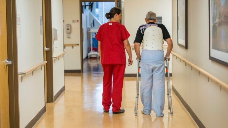 A nurse next to an elderly man with a walker