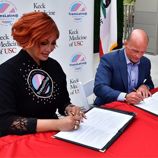 A TransLatin@ Coalition representative and a Keck Medicine representative signing documents