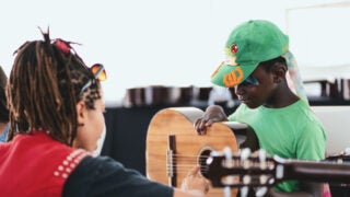 A teacher teaching a child how to play guitar. Photo/Courtesy of Fender Play Foundation