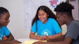 Students sitting and looking at a paper on a table in front of them.