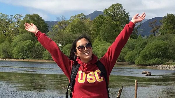 Girl with her hands up in front of a river.