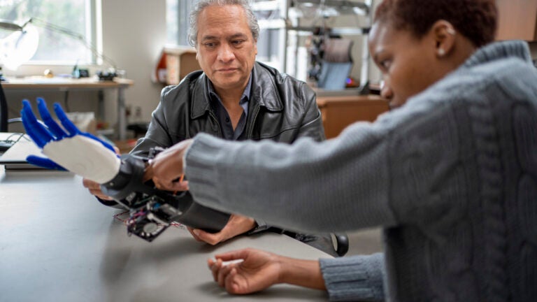 Student and Professor examining a robotic arm