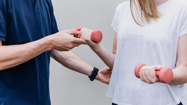 An occupational therapist works with a patient using weights.