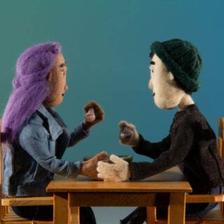 A clip of an animated film showing male and female puppets eating together