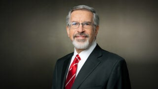 Leonard D. Schaeffer, in a black suit and red tie, against a plain background.