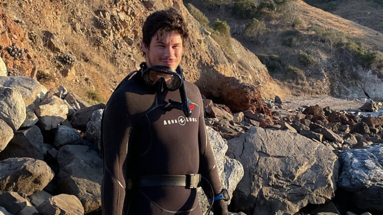 a student wearing a wet suit on the beach