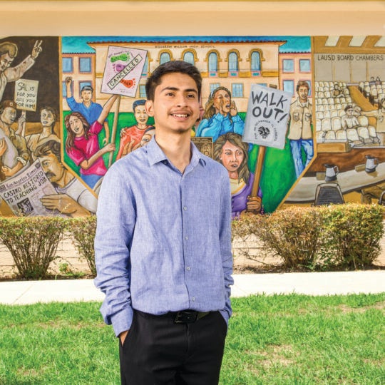 Student in front of a mural