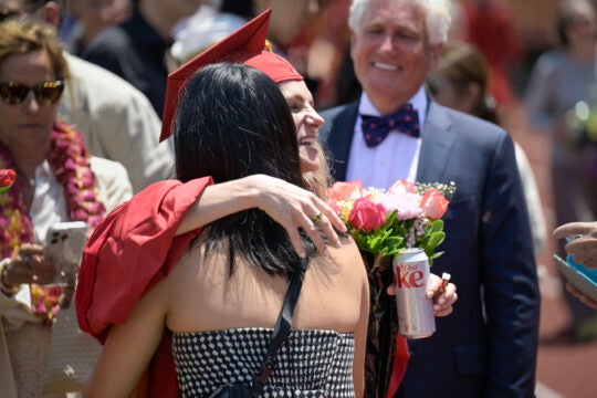 A graduating PhD student hugs a visitor at commencement festivities