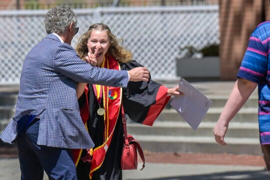 A graduating Trojan flashes the victory sign to one of her family members