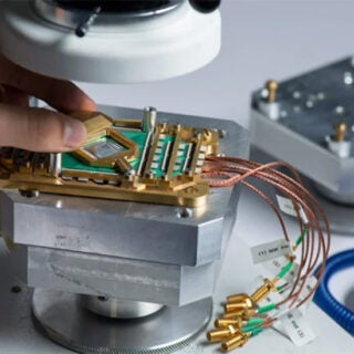 A researcher works on microchips under a scope