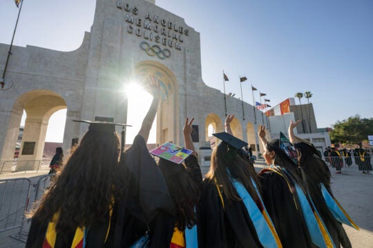 USC graduates give the Fight On sign at the Coliseum