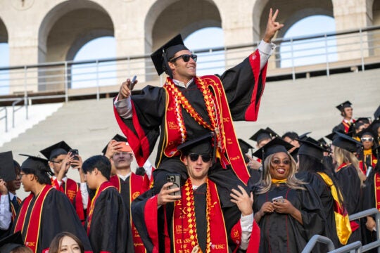 USC graduate sits on the shoulders of another USC graduate