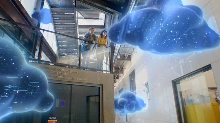 Two students overlook Iovine Young Academy lobby with computer generated clouds